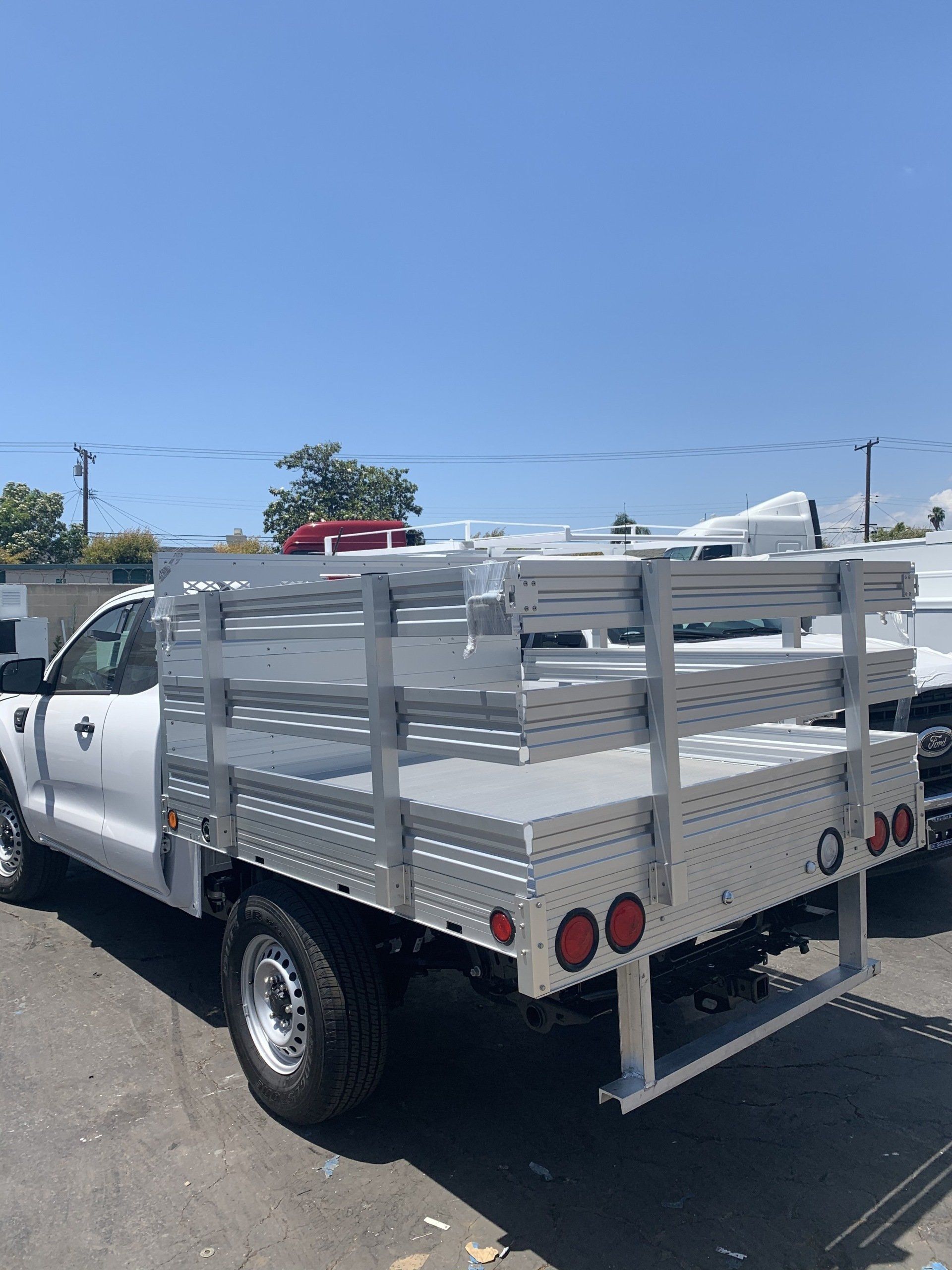White pickup truck with a flatbed in a sunny outdoor setting.