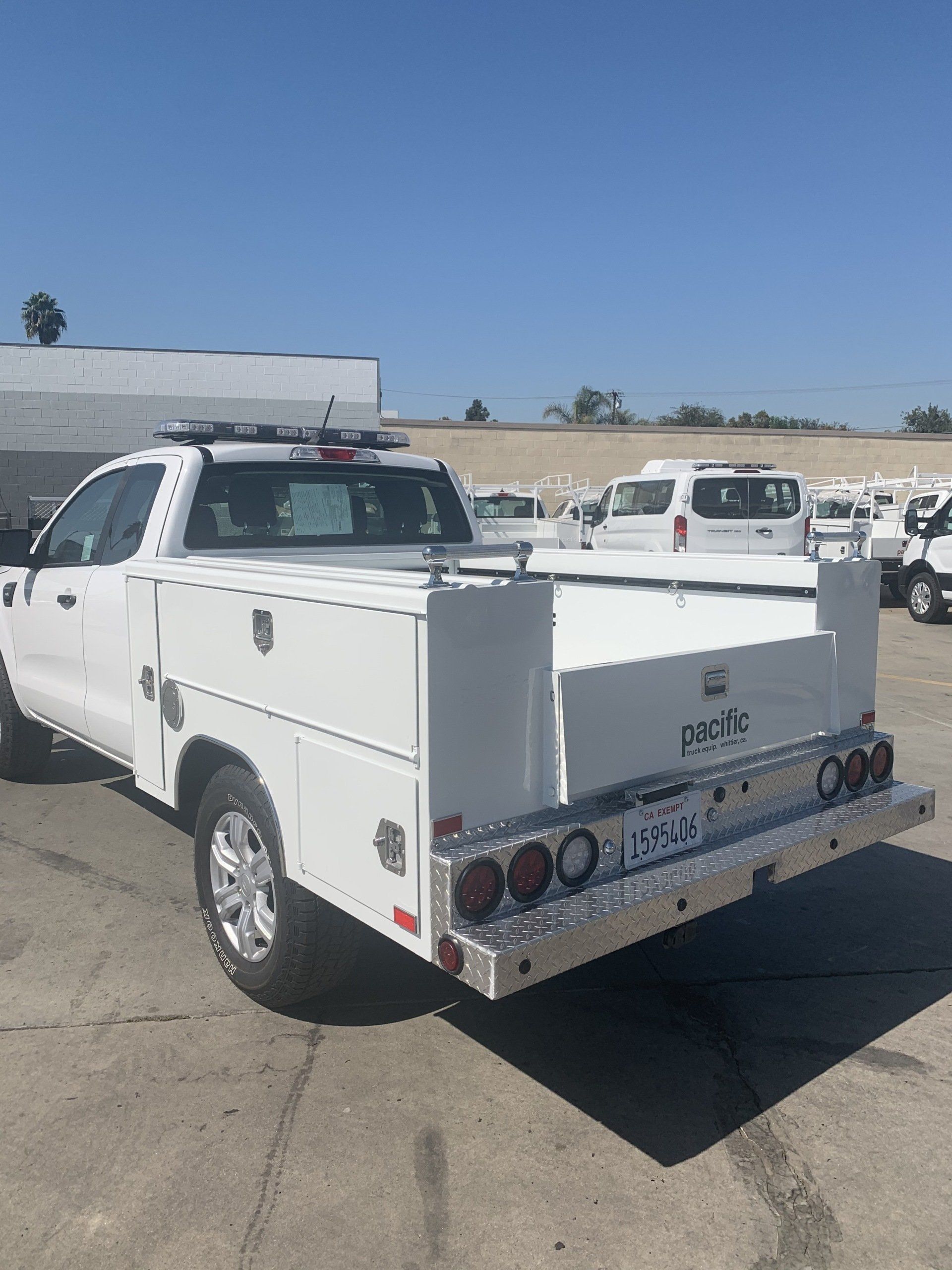 White utility truck with toolboxes, sunny outdoor setting.