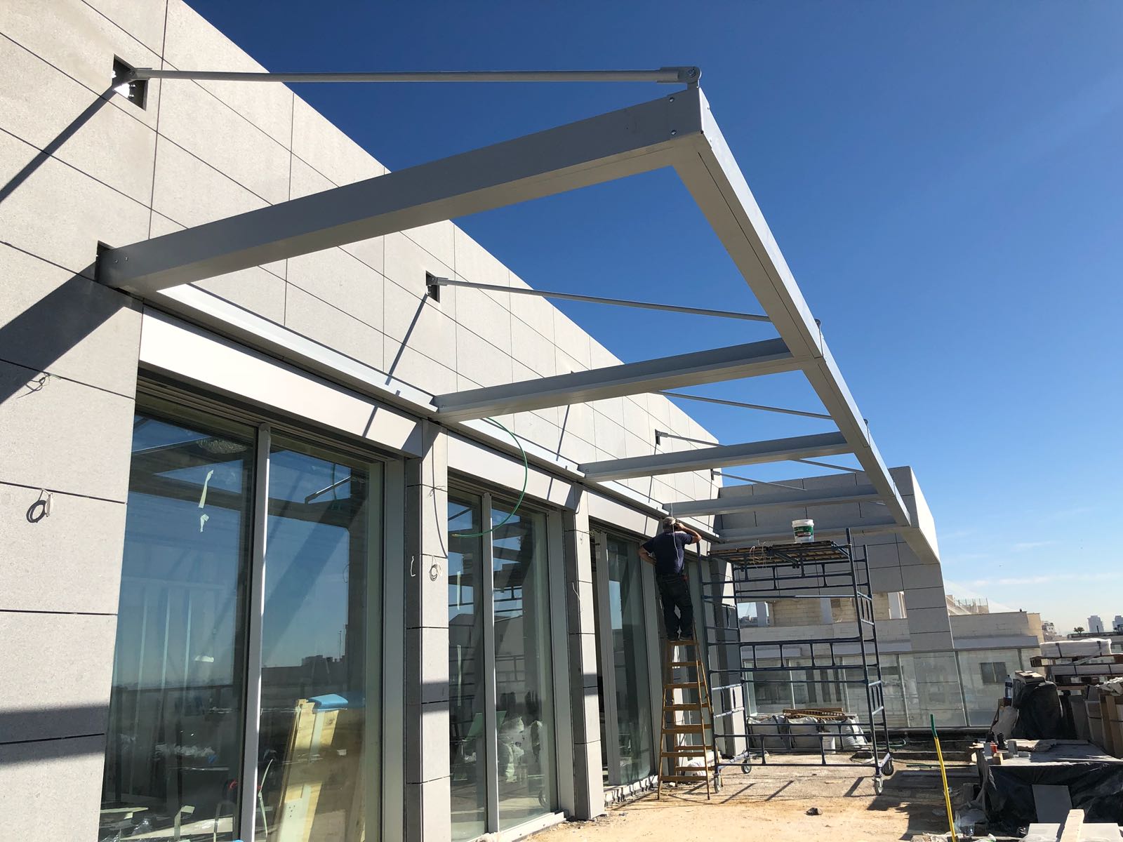 Modern building exterior with glass doors and steel awning under construction