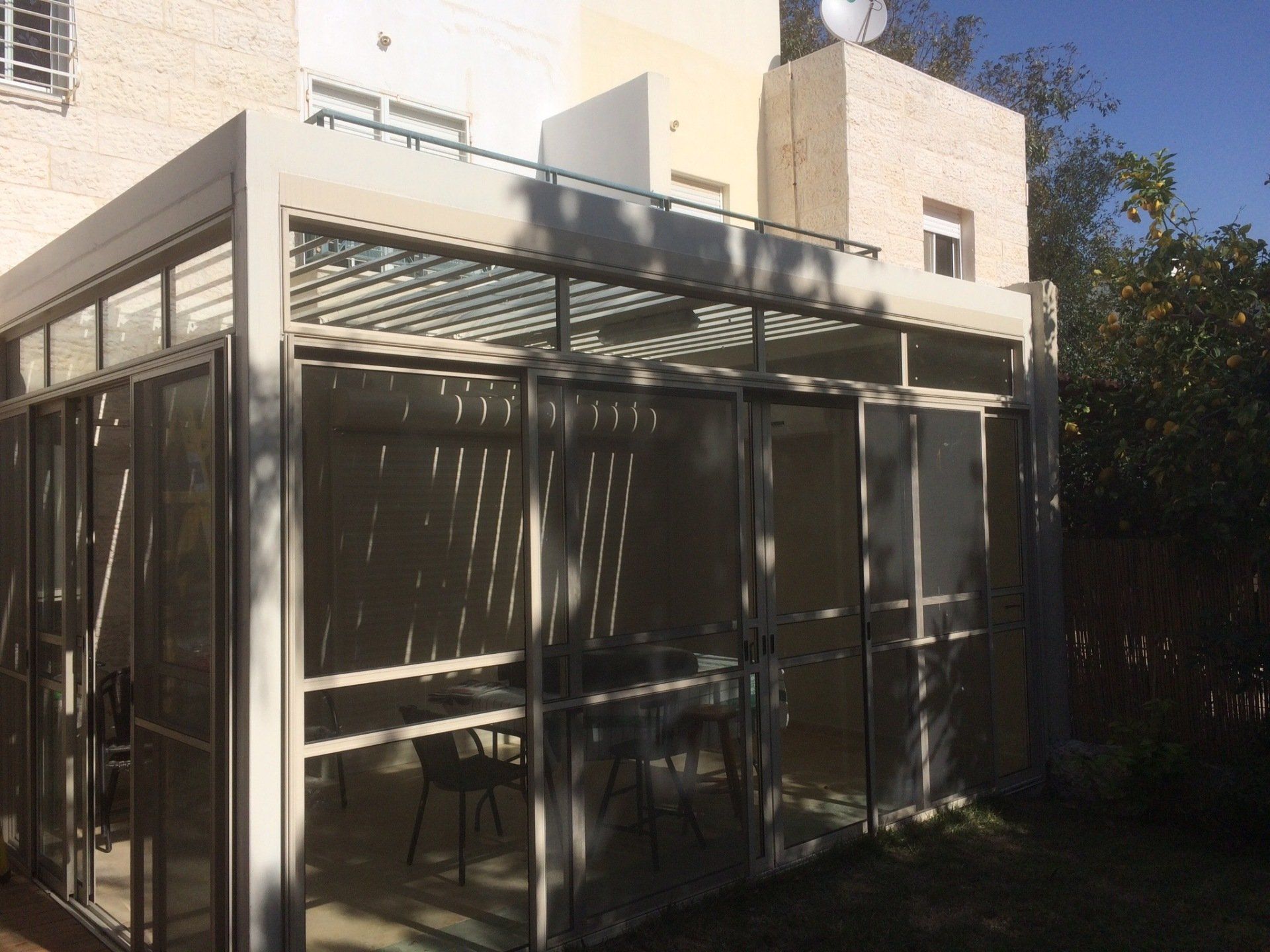 Modern house patio with glass walls and sliding doors, sunlit exterior