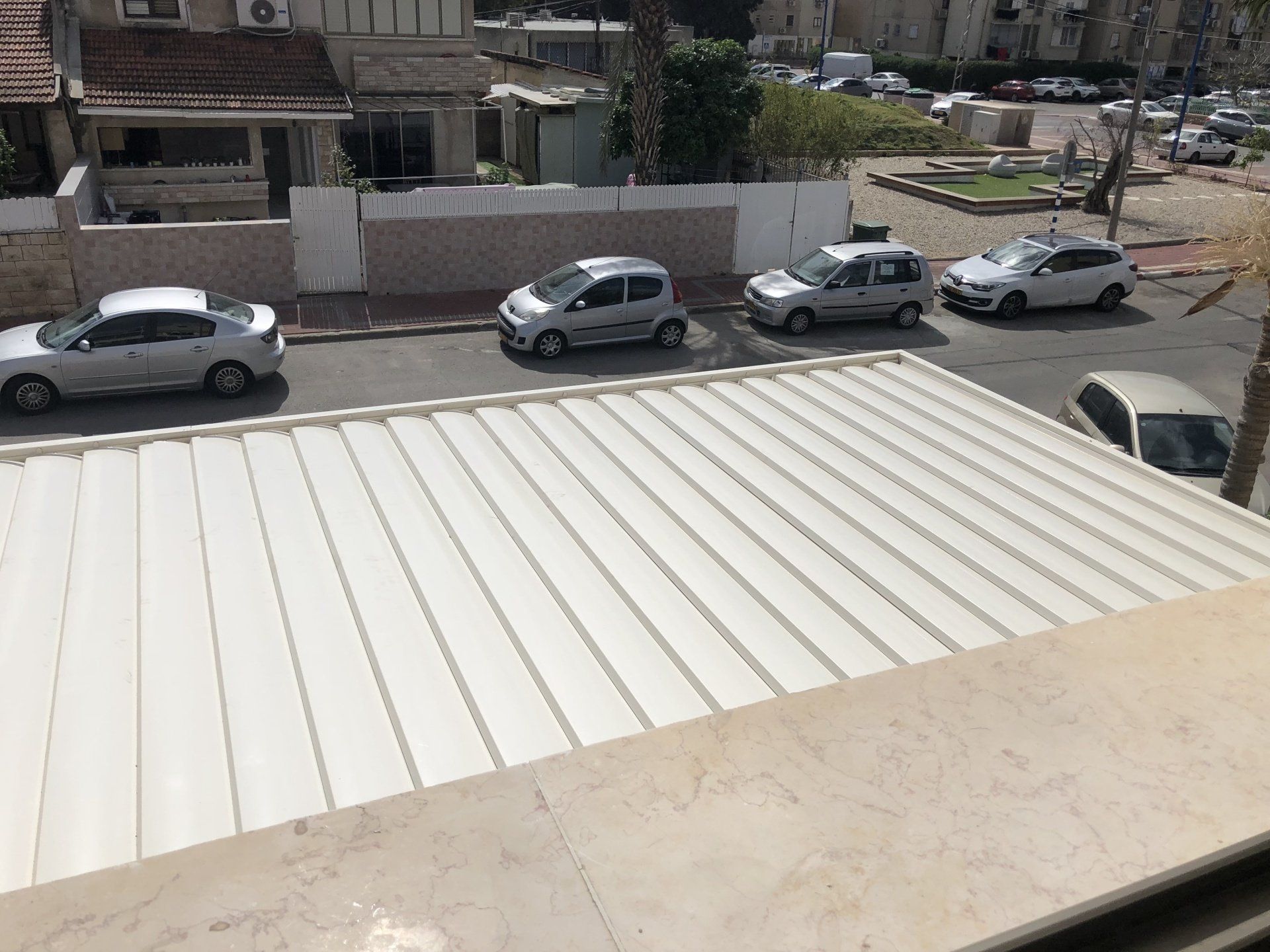 Street view from a rooftop with parked cars and buildings in the background