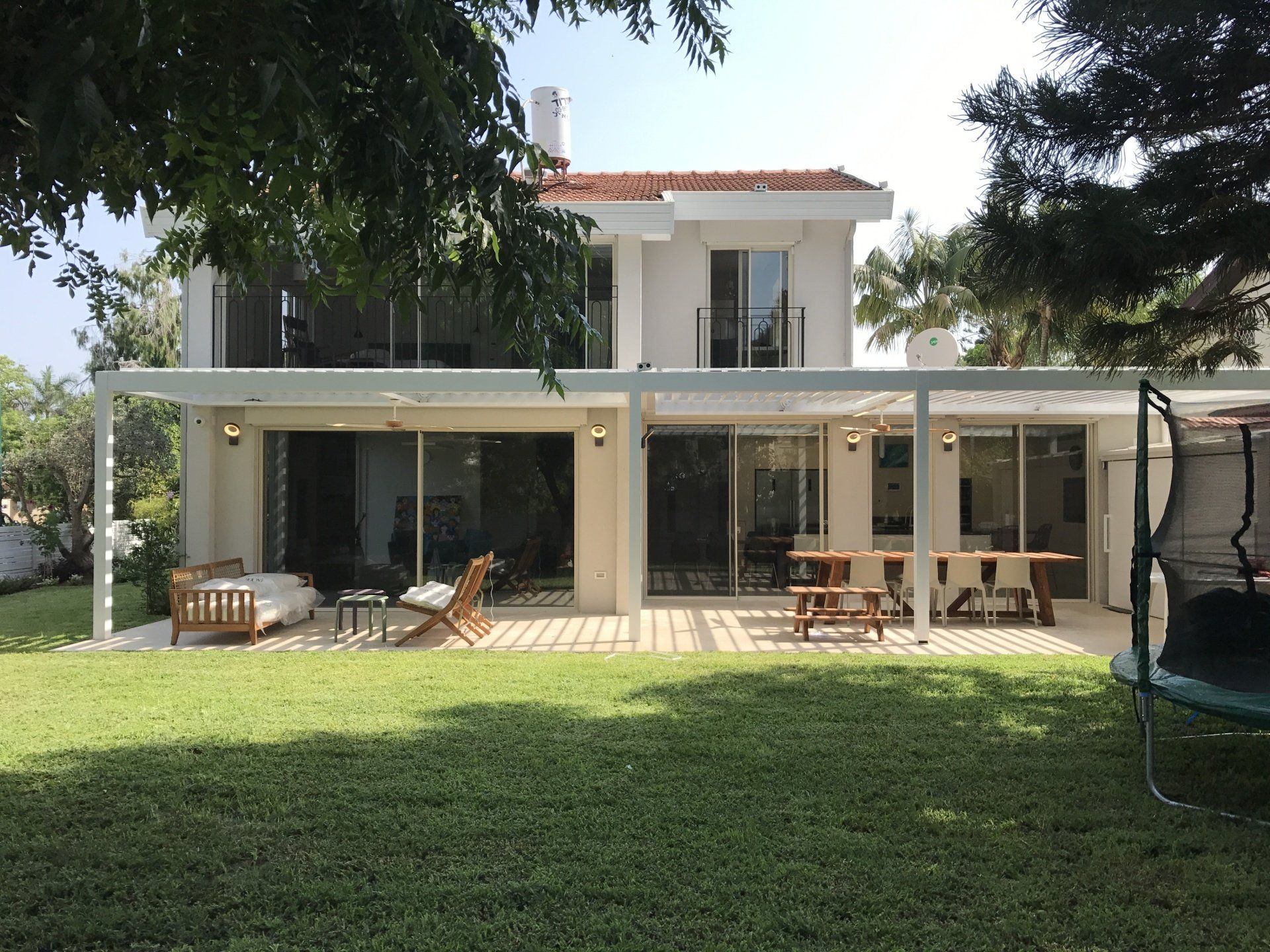 Modern two-story house with a covered patio and lawn, seen from the backyard