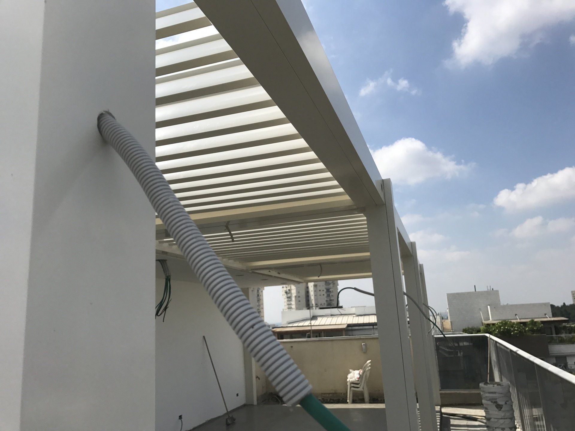 White building balcony with a striped awning and blue sky overhead