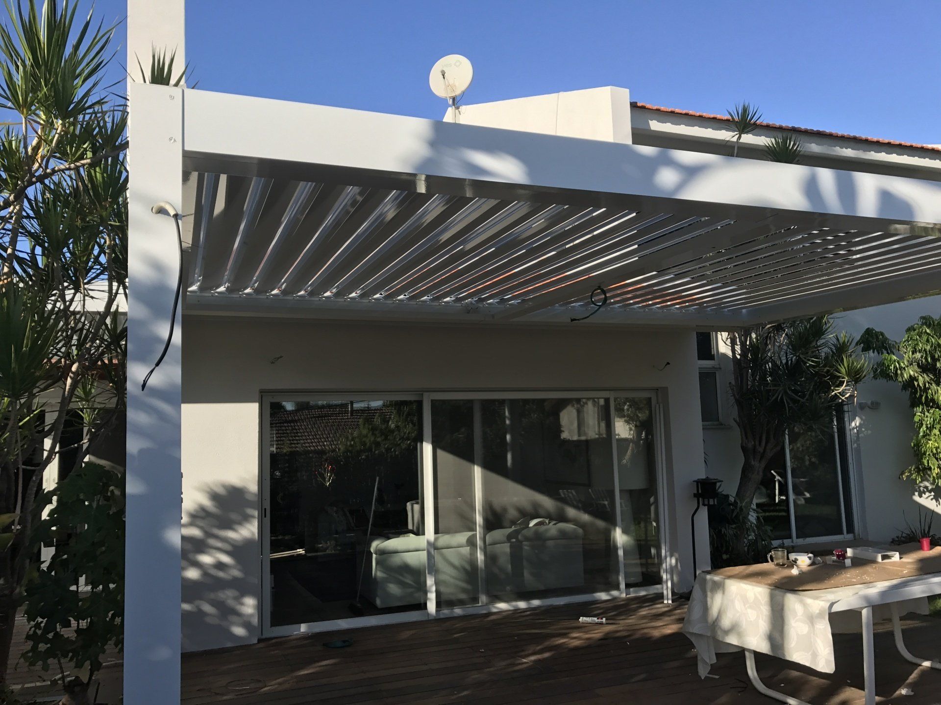 Modern patio with gray pergola, sliding glass doors, and outdoor table beside a home