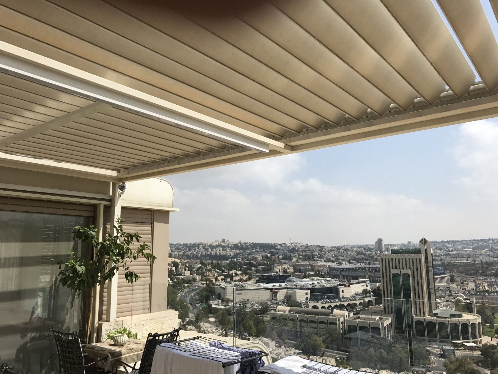 Covered rooftop terrace overlooking a dense cityscape under a bright sky