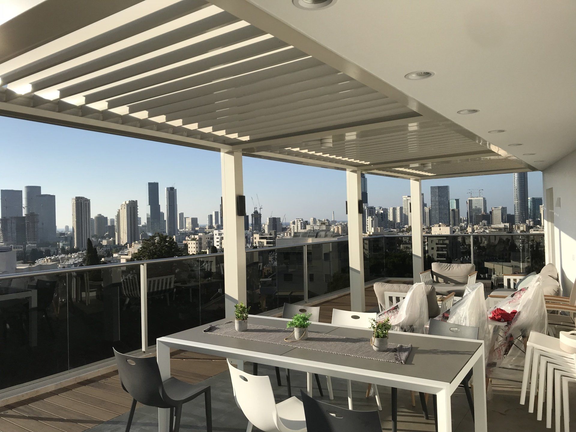 Modern outdoor patio with white furniture and city skyline view at sunset