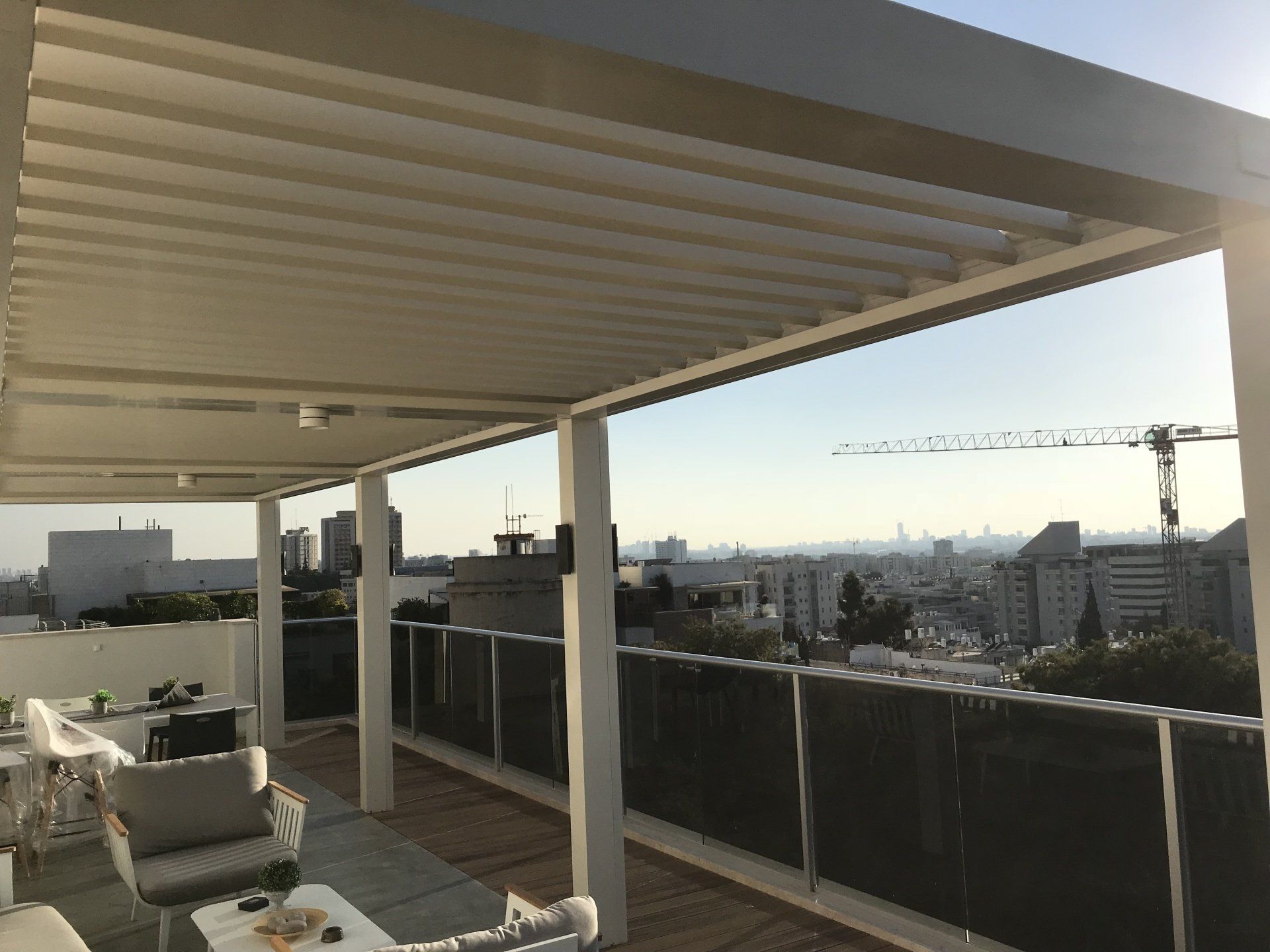 Covered rooftop patio with lounge chairs and city skyline view at sunset