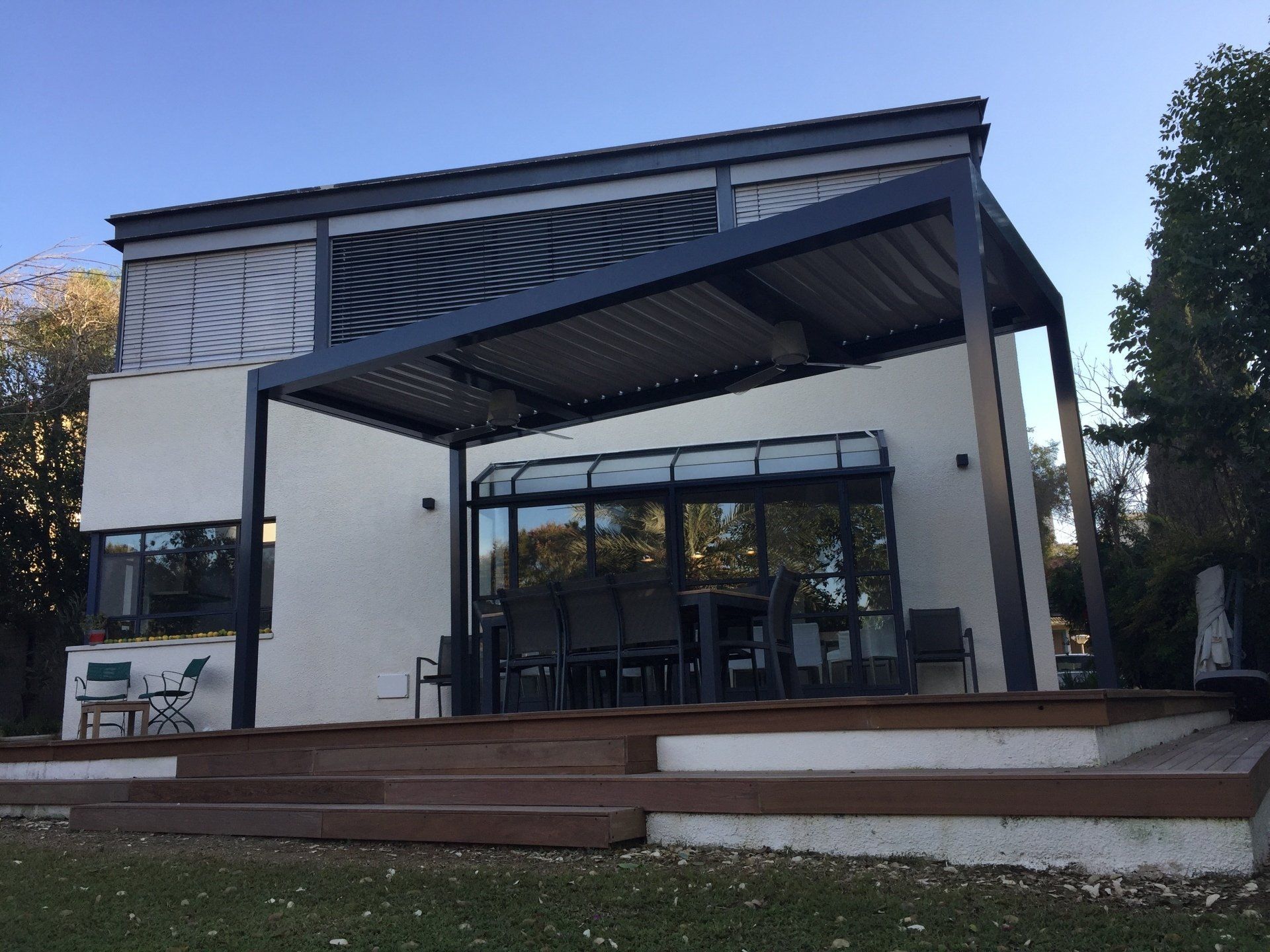 Outdoor patio pavilion with open sides, tables and chairs, and white walls at dusk