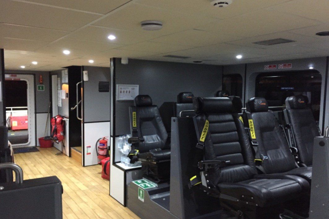 Compact gym interior with black exercise machines, wood flooring, and ceiling lights