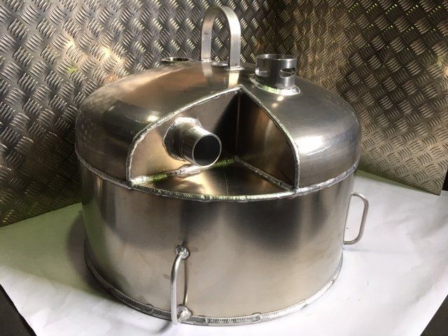 Stainless steel industrial container with lid, handle, and side pipe on a white surface in a metal workshop.