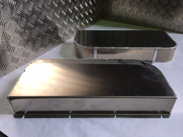 Two stainless steel rectangular containers on a textured metal surface, one in front and one behind.