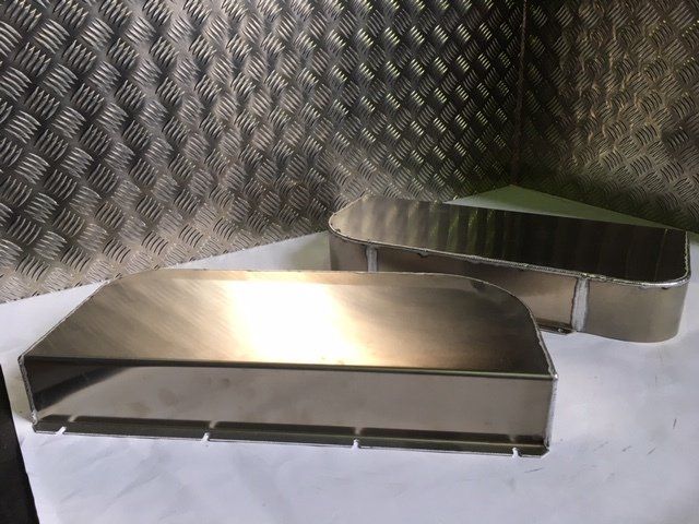 Two stainless steel trays on a metal countertop against a diamond-plate wall