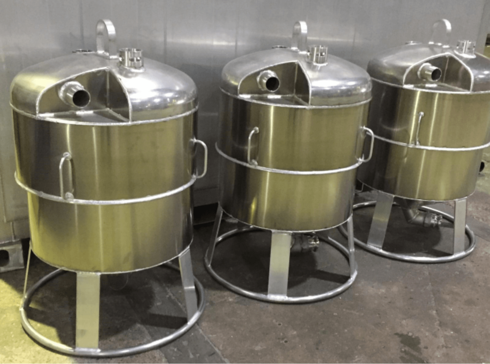 Three stainless steel industrial mixers on stands in a kitchen or food-prep area