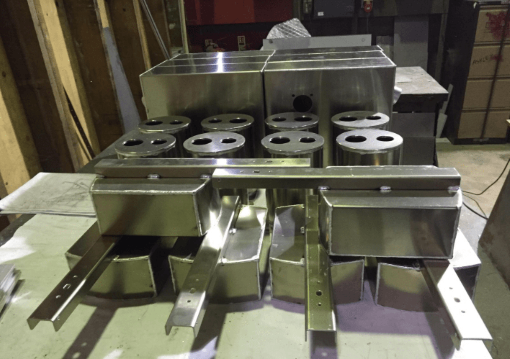 Stacked stainless steel metal parts on a workshop table with circular cutouts and legs