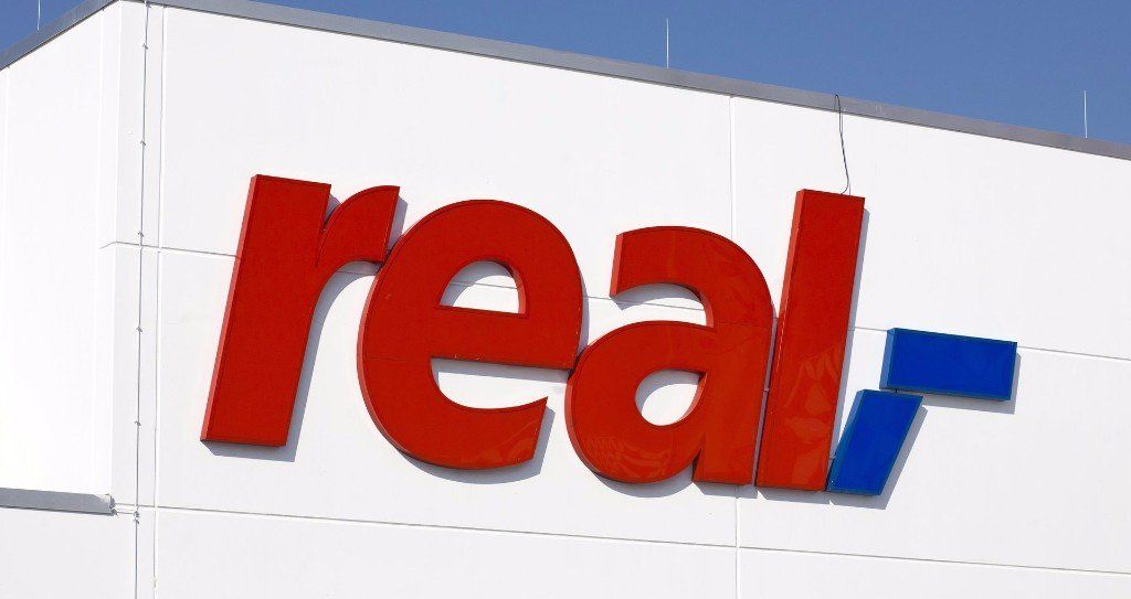 A red and blue sign that says real on a white building