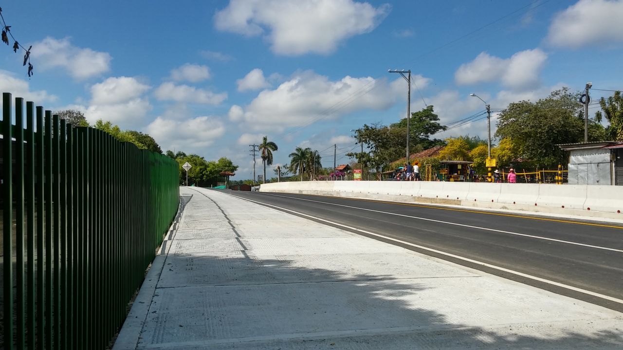 Un camino con una valla verde al costado.