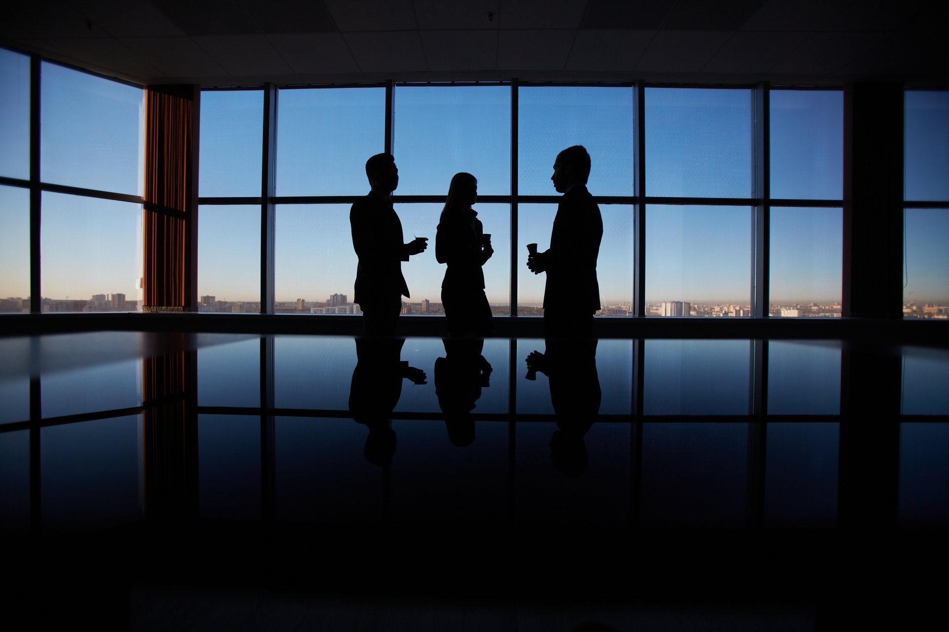 Tres personas están paradas frente a una gran ventana.
