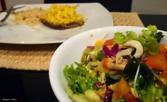 Un bol de ensalada junto a un plato de huevos revueltos.