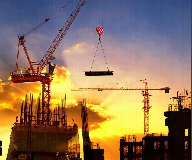 Un sitio de construcción al atardecer con una grúa levantando una viga