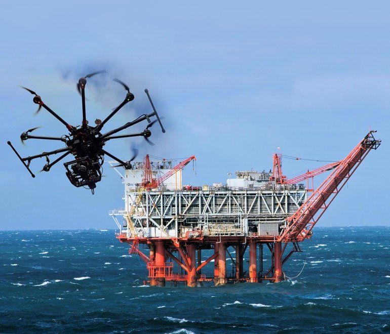 Un dron está volando sobre una plataforma petrolífera en el océano.
