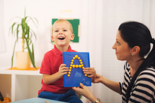 a woman is teaching a young boy how to write the letter a on a board .