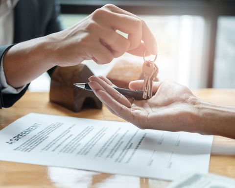 estate agent giving house keys to man and sign agreement in office