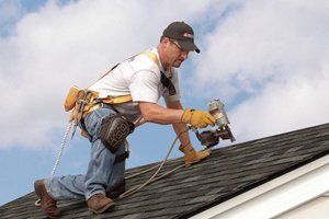 man nailing shingles using nail gun
