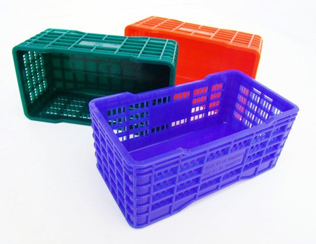 Tres cestas de plástico de diferentes colores sobre un fondo blanco.