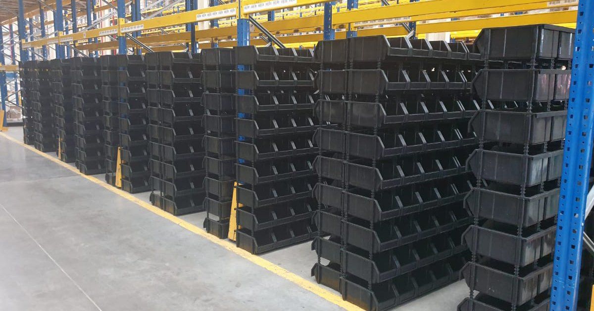 Un almacén lleno de contenedores negros apilados uno encima del otro.