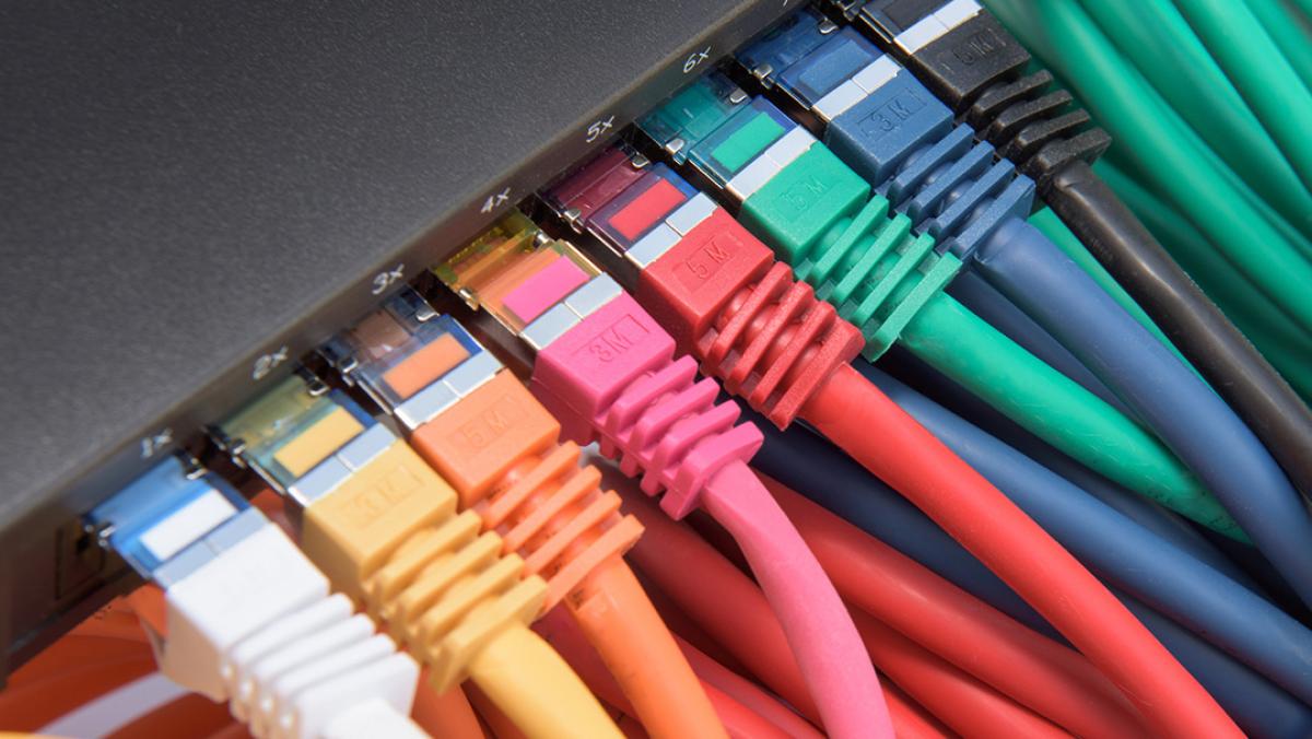 Un montón de cables Ethernet de diferentes colores están conectados a un enrutador.