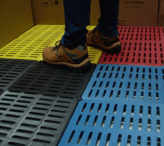 Los pies de una persona están parados sobre un piso de baldosas de colores.