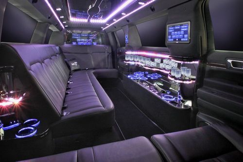 Inside of a black limousine with purple lighting and leather seats.