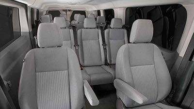 Interior of a passenger van with multiple gray seats and windows.