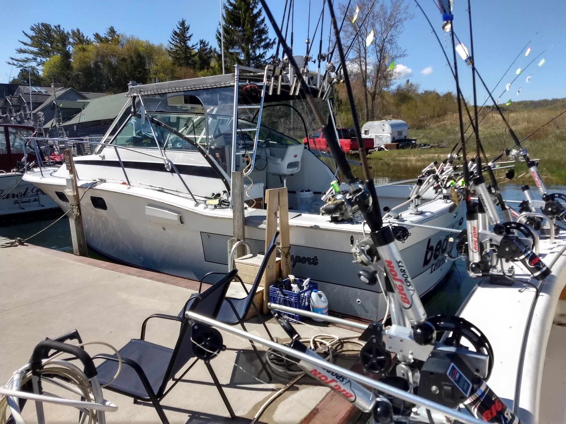 Fishing boats docked at a marina with rods mounted on the stern under a sunny sky