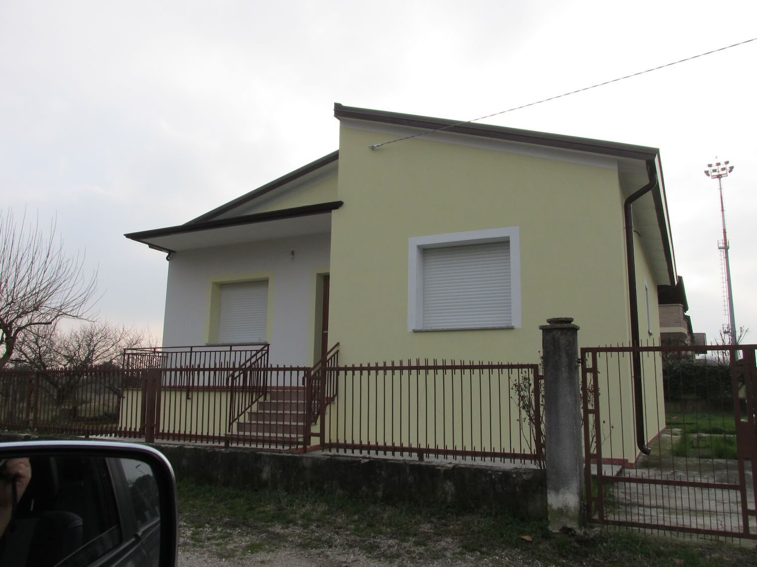 Una casa gialla e bianca con una recinzione davanti