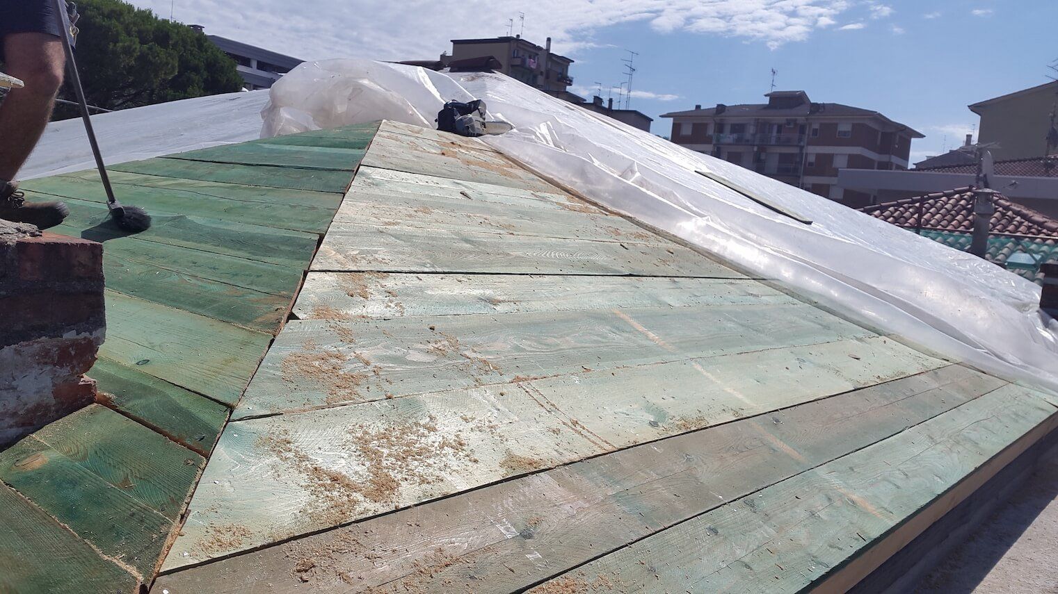 Una persona sta lavorando su un tetto ricoperto di plastica.