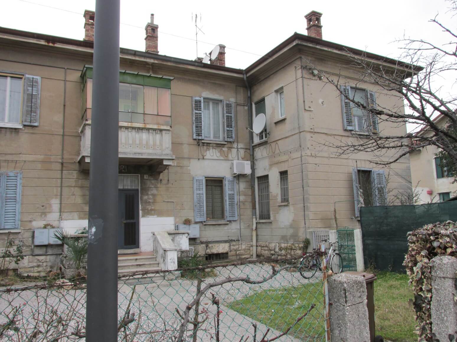 Un edificio con una recinzione e una bicicletta di fronte