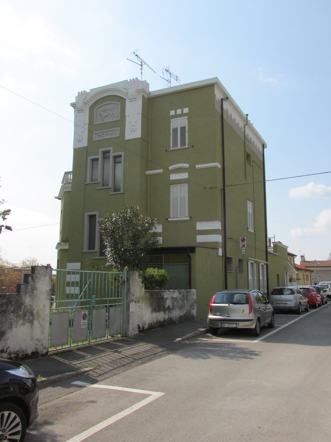 Un edificio verde con le auto parcheggiate di fronte