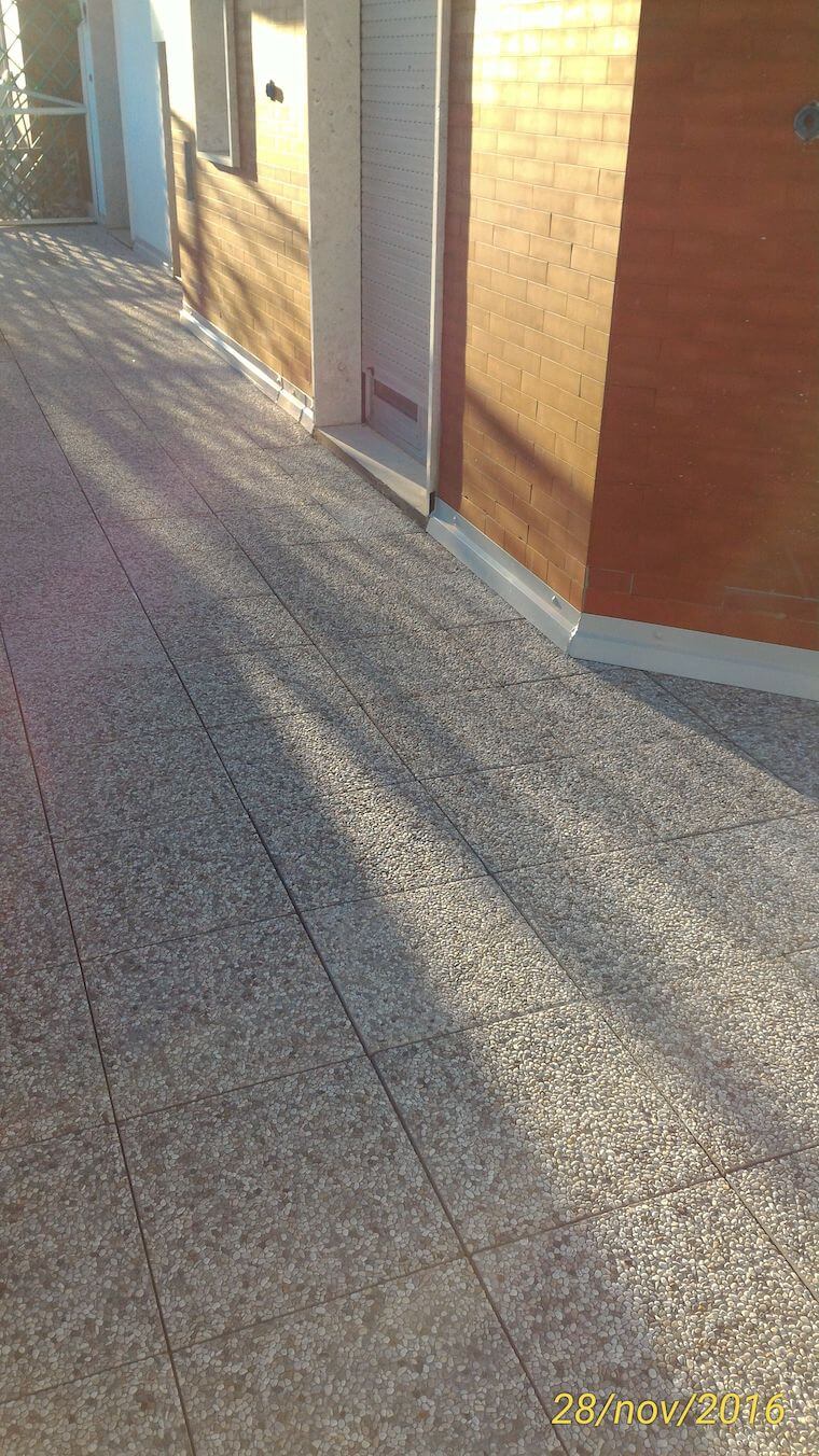 Un marciapiede che conduce a un edificio con un muro di mattoni e una porta.
