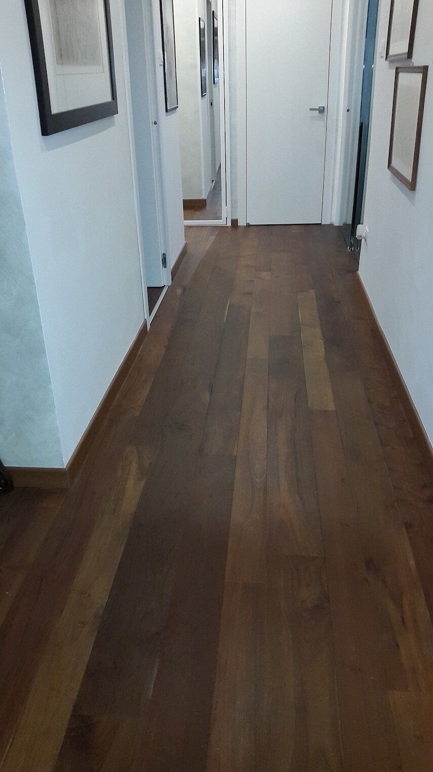Un lungo corridoio con pavimento in legno e pareti bianche.