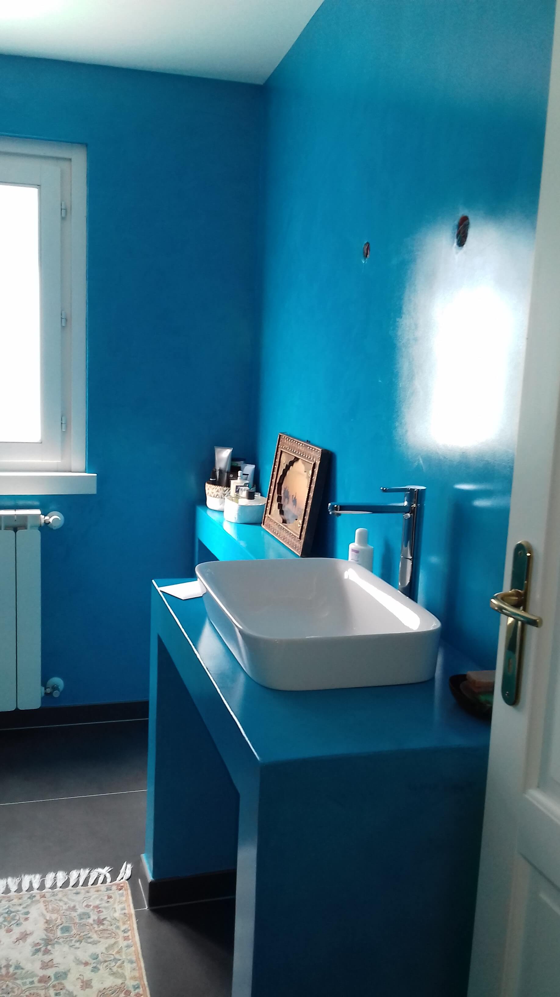 Un bagno con pareti blu e un lavandino bianco.