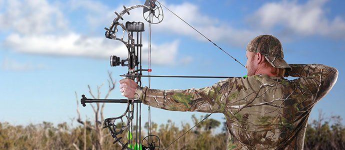 man in camo hunting with bow