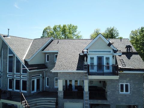 large grey brick home with cross gabled roof under construction
