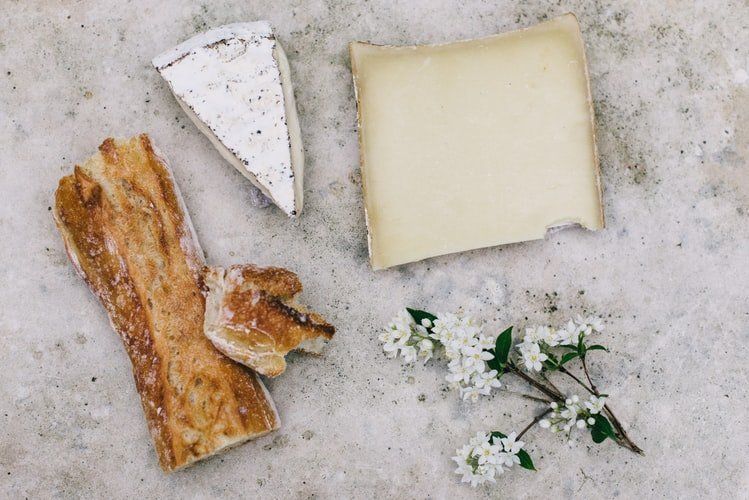 Une variété de fromages, de pain et de fleurs sont sur une table.