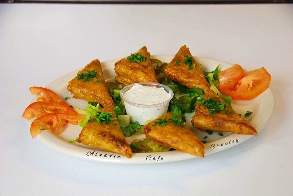 a plate of food with a dipping sauce and tomatoes on a table .