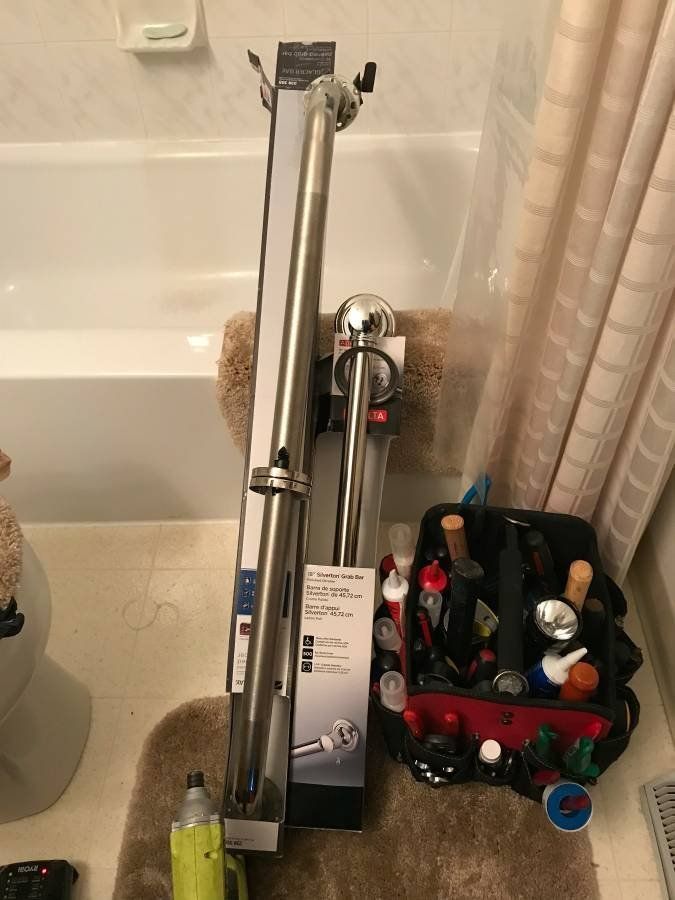 Bathroom with a bathtub, shower bar, toolbox, and toilet.