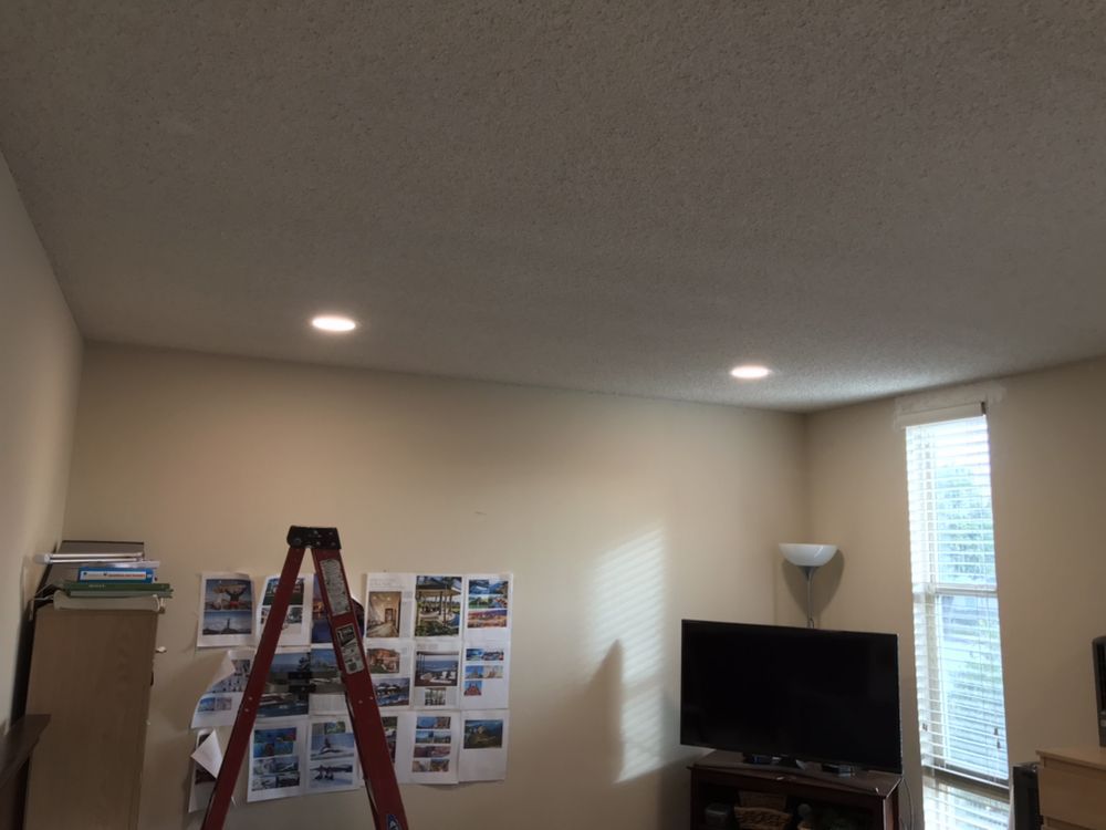 Interior of a room with two recessed lights in the ceiling, a television, and a ladder.