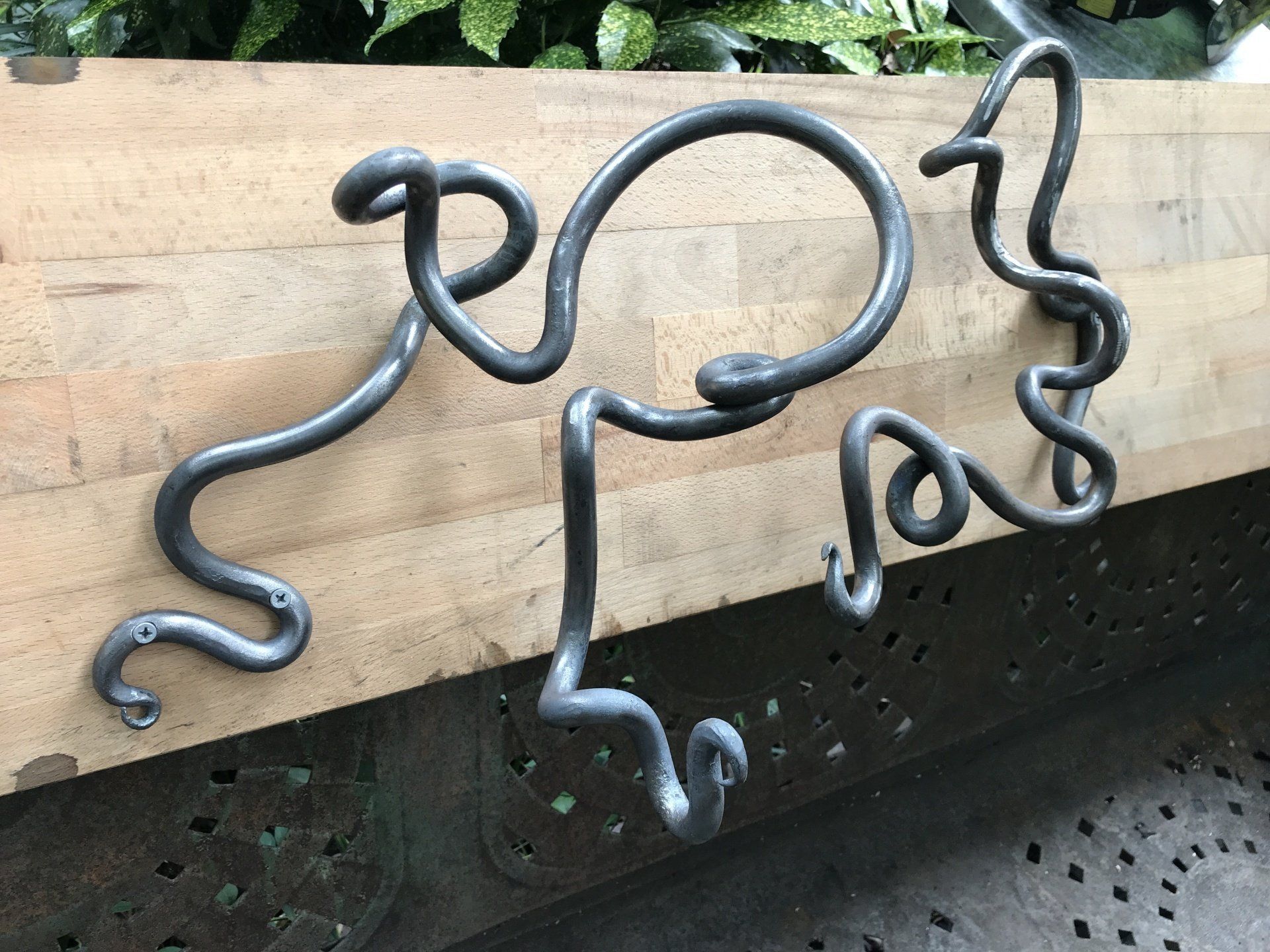 A piece of metal that looks like a snake is sitting on a wooden surface.