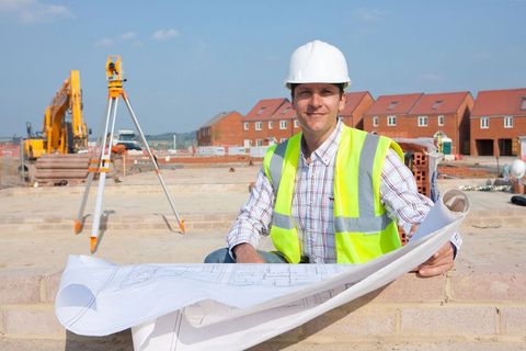 C92GC1 Portrait of smiling architect with blueprints at construction site