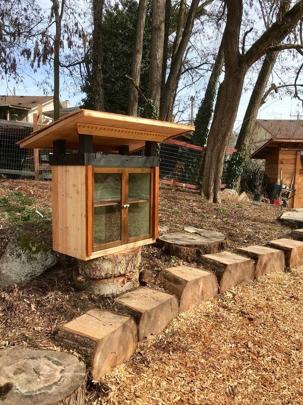 A wooden box with a roof is sitting on top of a pile of wood chips.